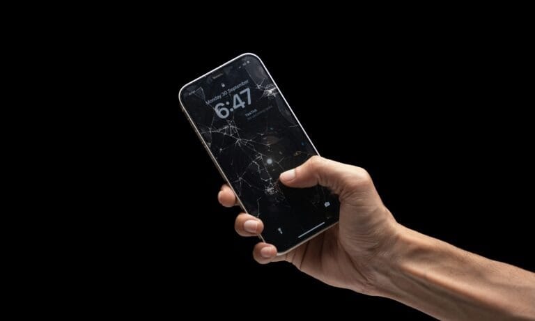 Mano che tiene uno smartphone con lo schermo danneggiato e incrinato
